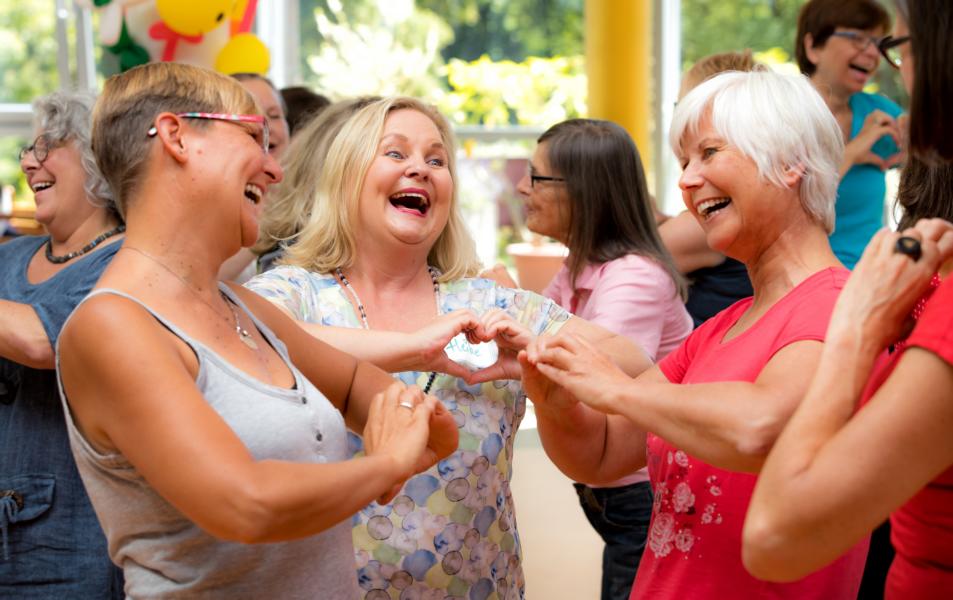 Menschen lachen miteinander, sie haben Spaß zeigen mit den Händen Herzen