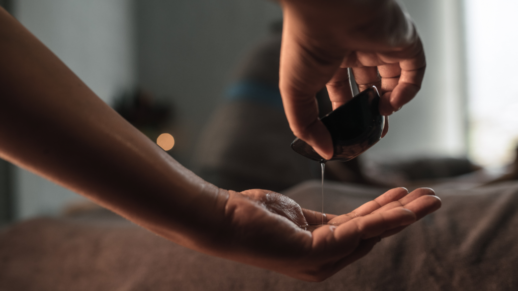 Massagetherapeutin träufelt warmes Öl in ihre Handfläche, bereit für eine Massage – Touch Experience Ansbach