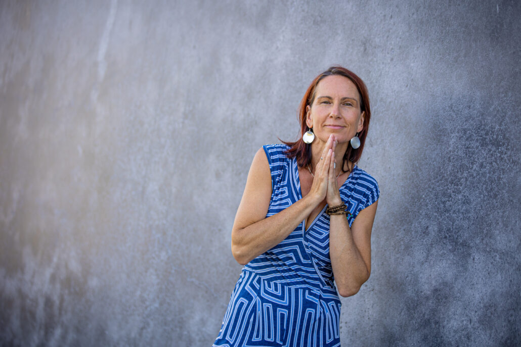 Life Coach Martina Stöhr-Burkhardt aus Ansbach lächelt mit zusammengelegten Händen vor einer Betonwand