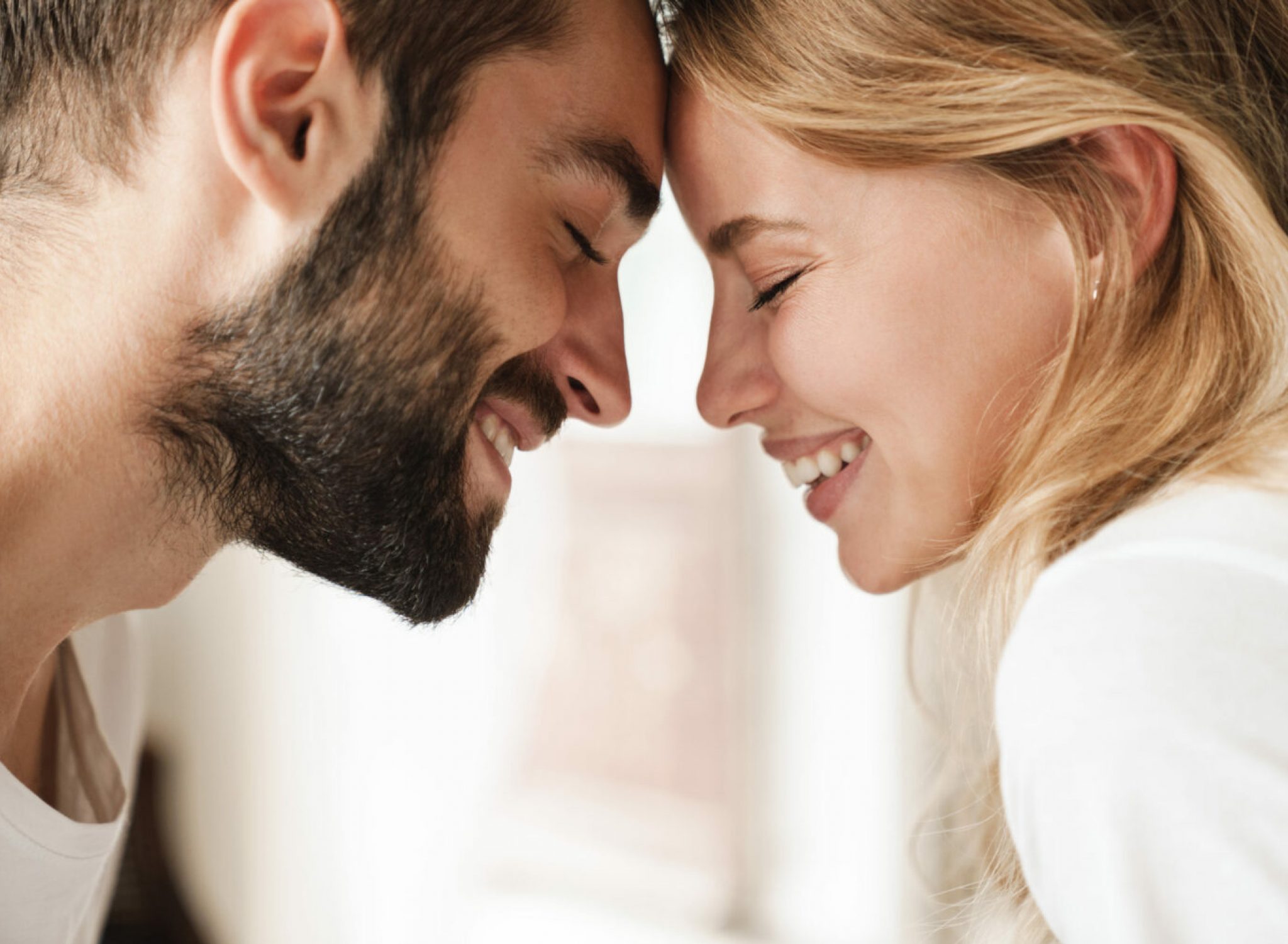 Close up of a beautiful happy young couple relaxing at home, embracing