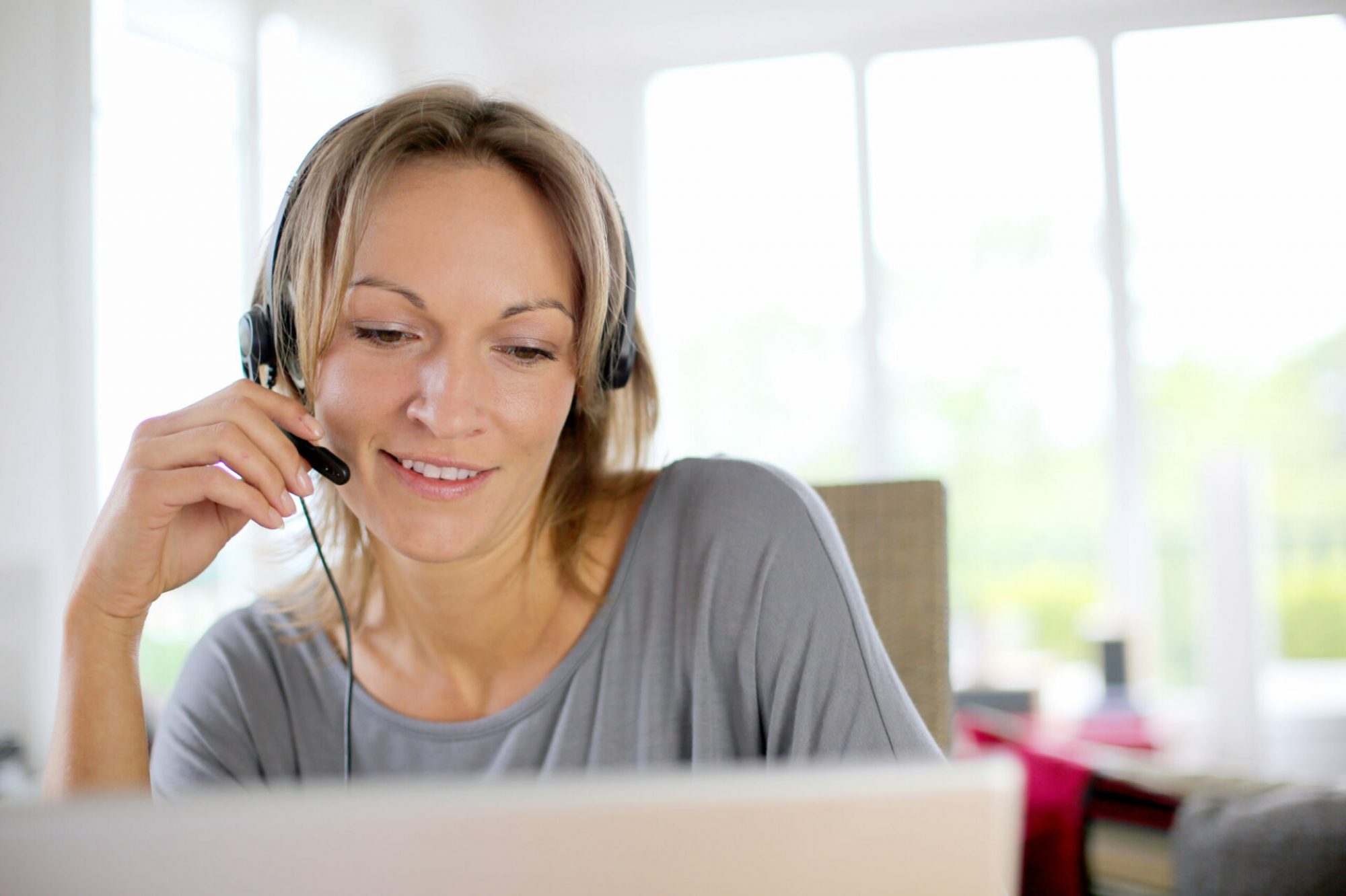 Portrait of woman with headset in front of laptop Portrait of woman with headset in front of laptop